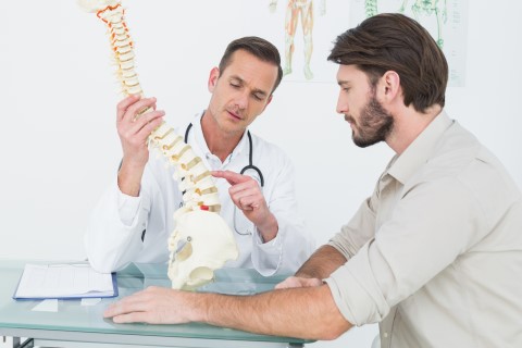 Imagen de un doctor de lesiones musculares explicando una lesión en la columna por un accidente de carro.